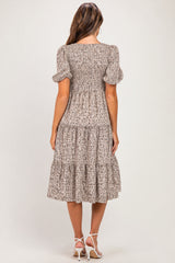 woman wearing a floral print maternity dress with puff sleeves and a tiered hem, showing her baby bump from the back