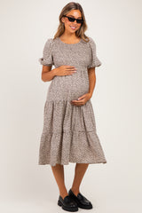 woman wearing a floral print maternity dress with puff sleeves and a tiered skirt, holding her baby bump
