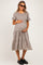 woman wearing a floral print maternity dress with puff sleeves and a tiered skirt, holding her baby bump