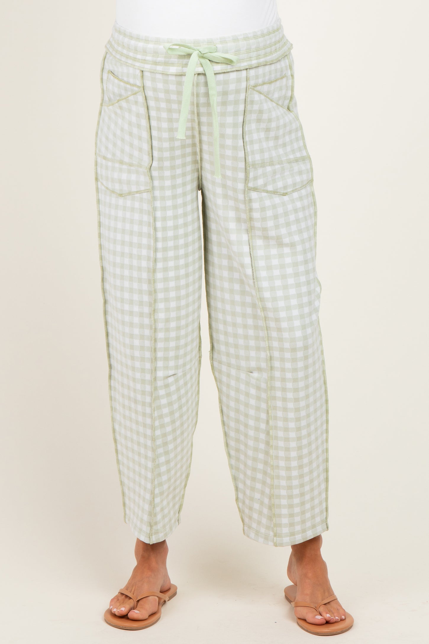 woman wearing green and white gingham maternity pants with pockets and a drawstring waist