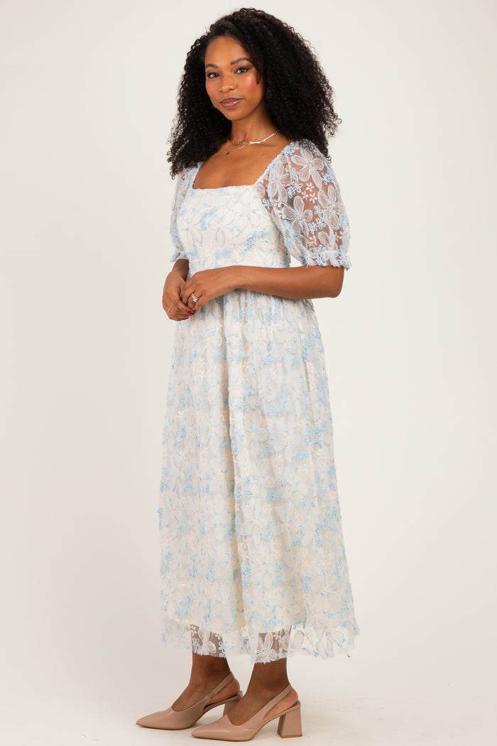 woman wearing a light blue floral lace midi dress with puff sleeves and nude high-heeled shoes