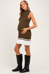 woman wearing a ribbed olive green maternity dress with a white and brown striped hem and holding her baby bump