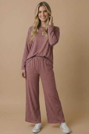 woman wearing a maroon and cream striped long sleeve top and matching wide-leg pants, posing casually