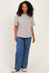woman wearing a striped short sleeve top and wide leg blue jeans, smiling at the camera