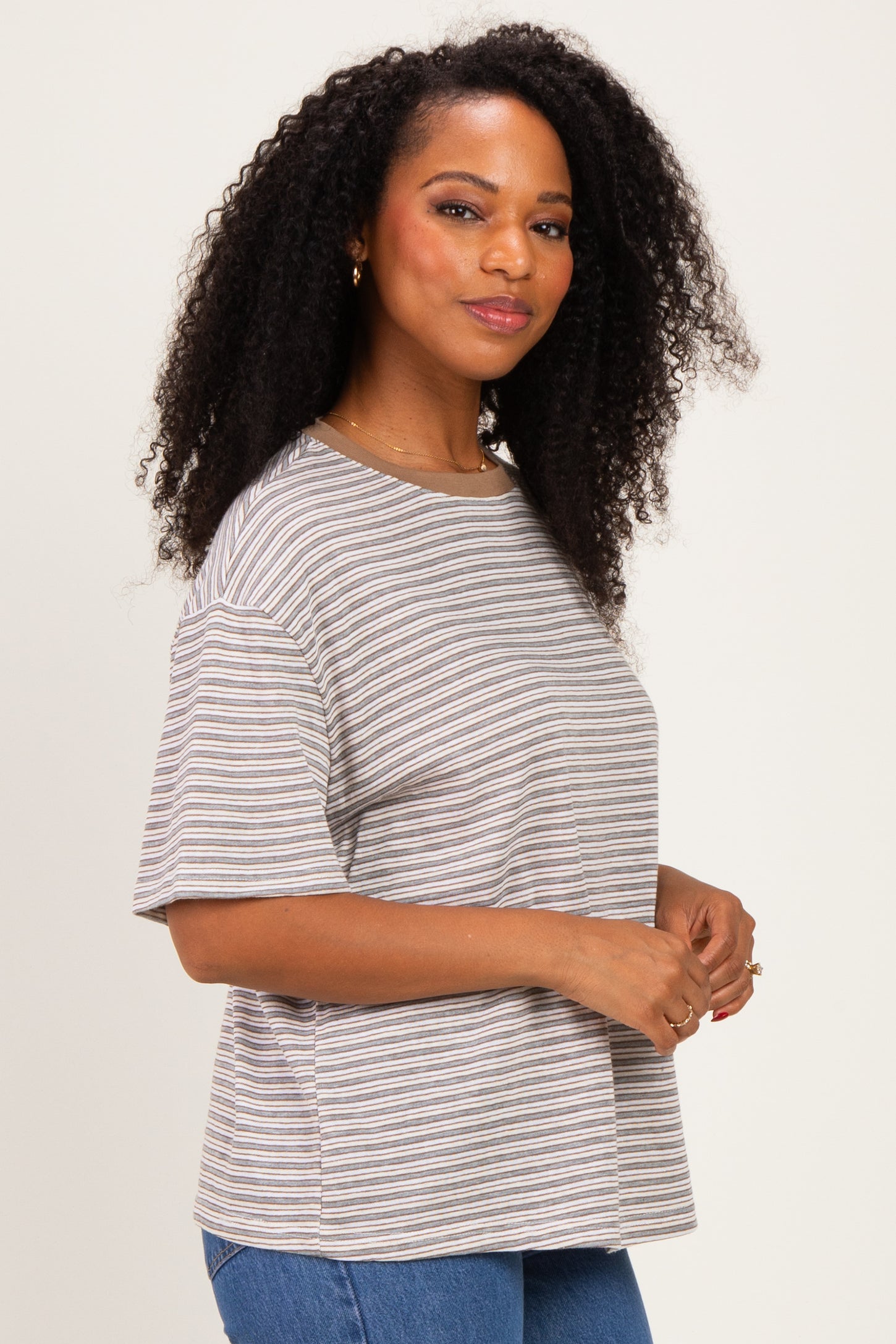 woman wearing a striped short sleeve t-shirt in neutral tones with a relaxed fit and curly hair