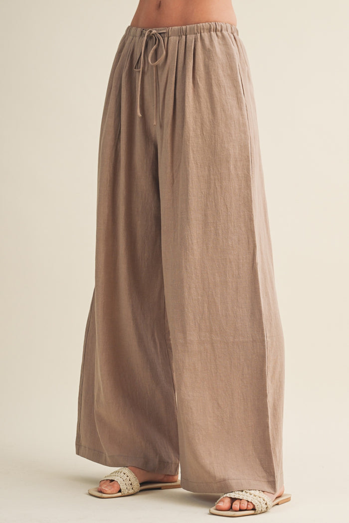 woman wearing beige wide-leg linen pants with an elastic waistband and drawstring detail