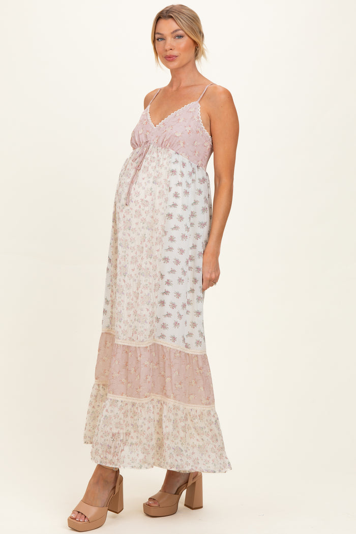 woman wearing a pink and white floral maternity maxi dress with a tiered skirt and a visible baby bump