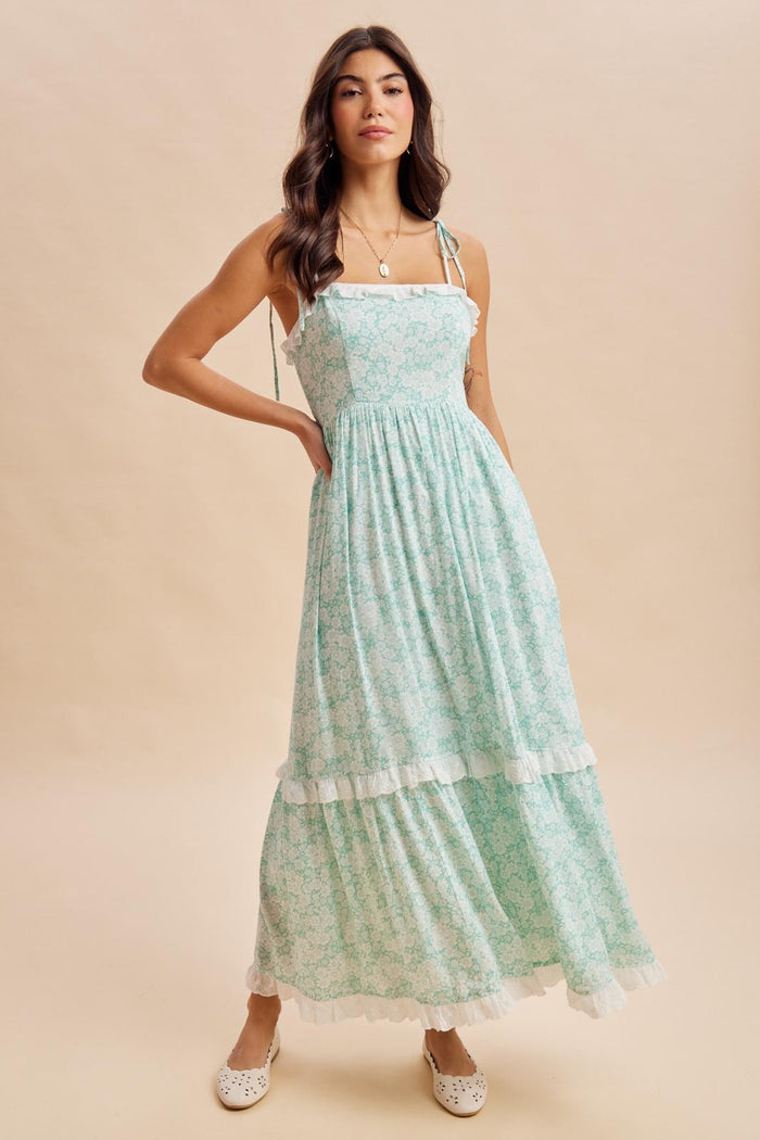 woman wearing a teal floral maxi dress with ruffled straps and a tiered skirt, styled with white flats