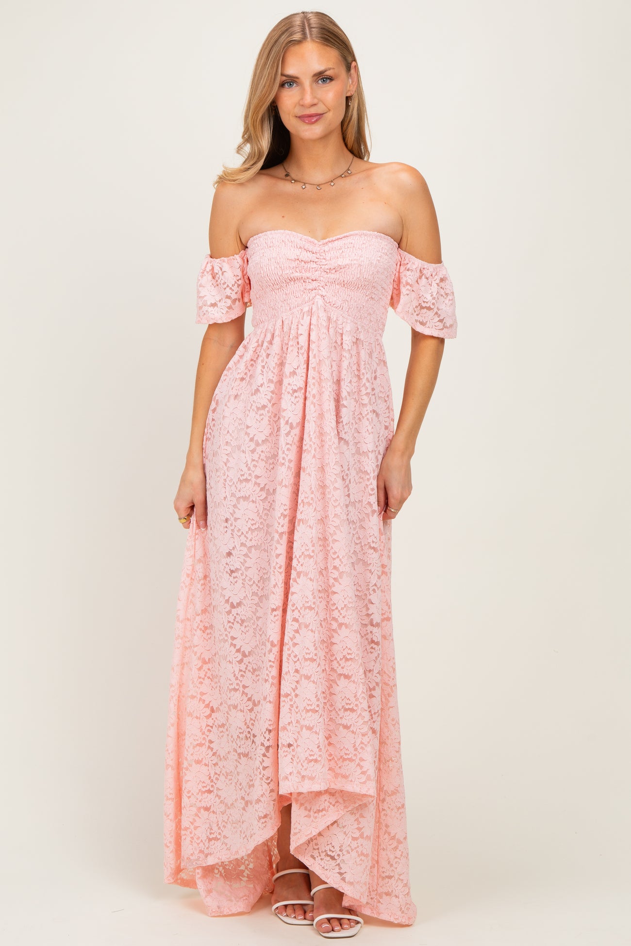 woman wearing a light pink off-the-shoulder lace maxi dress with flutter sleeves and a high-low hemline