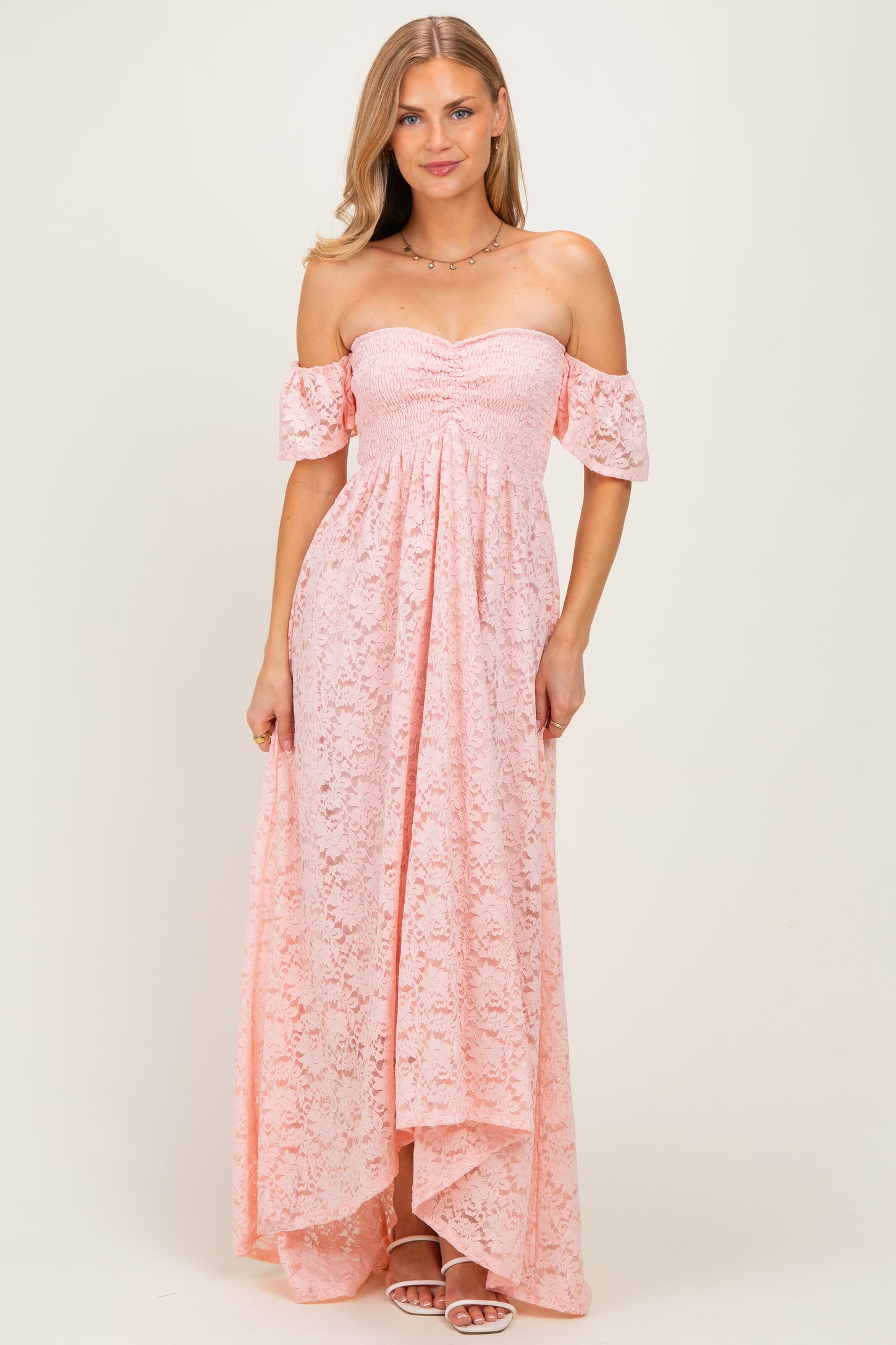 woman wearing a light pink off-the-shoulder lace maxi dress with flutter sleeves and a high-low hemline
