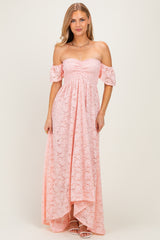 woman wearing a light pink off-the-shoulder lace maxi dress with flutter sleeves and a high-low hemline