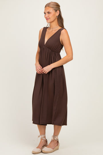 woman wearing a brown pleated midi dress with a deep v-neckline and a relaxed fit