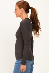 woman wearing a dark gray ribbed long sleeve top styled with fitted jeans