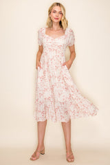 woman wearing a light pink floral midi dress with puff sleeves and pockets