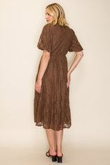 woman wearing a brown lace midi dress with short sleeves and a cinched waist, shown from the back
