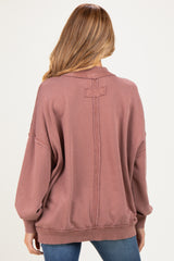 woman wearing a mauve oversized maternity sweatshirt with a relaxed fit and distressed detailing on the back