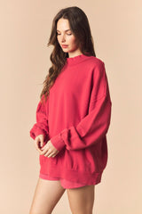 woman wearing a loose-fitting bright pink sweatshirt with long sleeves and a crew neckline