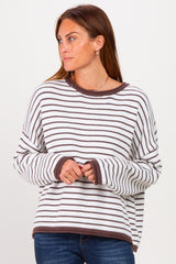 woman wearing a white and brown striped oversized sweater with long sleeves and a relaxed fit
