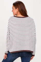 woman wearing a striped white and brown oversized sweater, showing the back view, paired with blue jeans