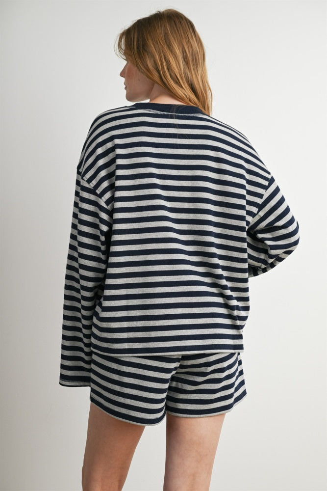woman wearing a navy and white striped oversized long sleeve top and matching shorts