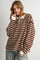 woman wearing a brown and cream striped oversized long sleeve top with a collar and button detail