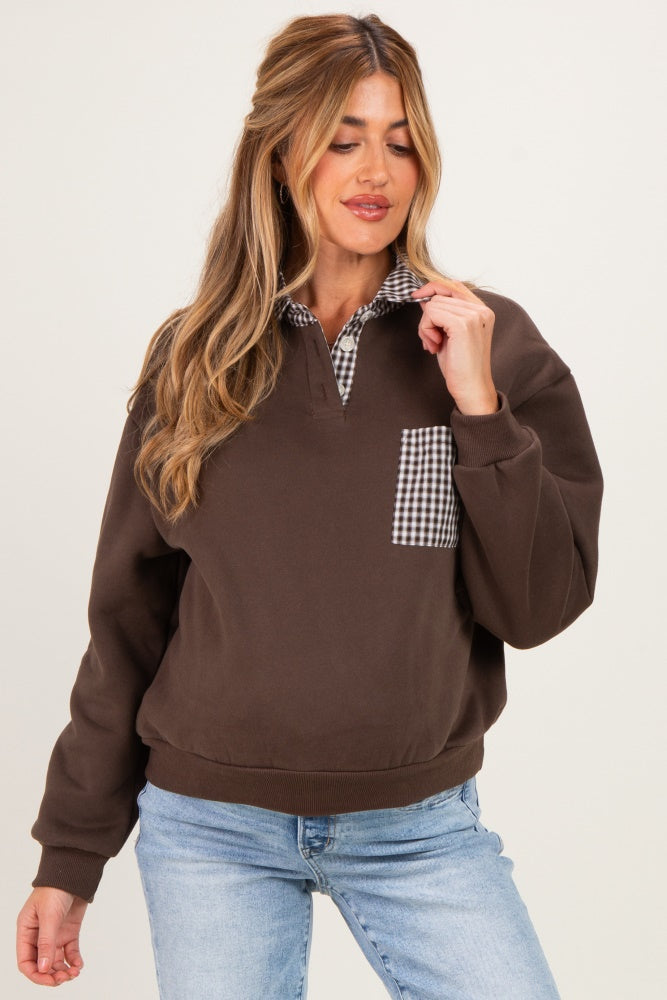 woman wearing a brown maternity sweatshirt with a checkered collar and pocket, styled with light blue jeans