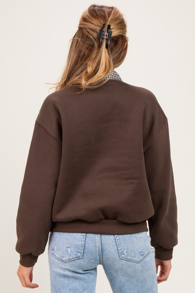 woman wearing a brown maternity sweatshirt with a relaxed fit and dropped shoulders, styled with blue jeans