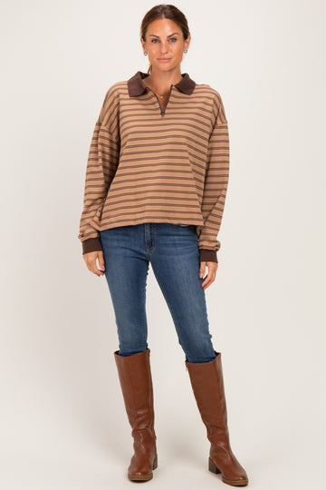 woman wearing a brown striped long sleeve polo top with a brown collar, paired with blue skinny jeans and brown knee-high boots