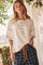 woman wearing a cream short sleeve top with button details and relaxed fit, paired with plaid shorts