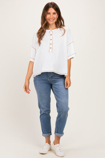 woman wearing a white maternity top with button details and rolled sleeves paired with light blue jeans
