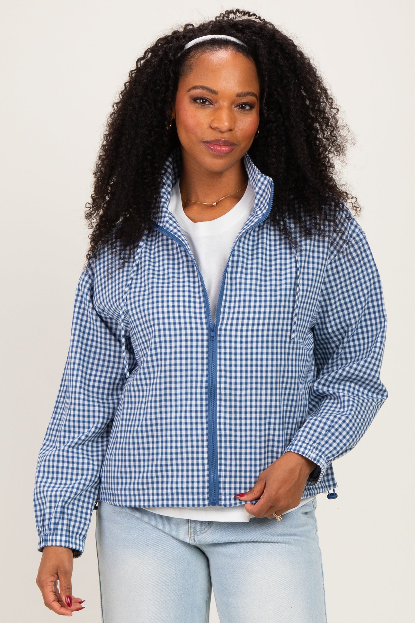 woman wearing a blue and white checkered zip-up jacket and light blue jeans