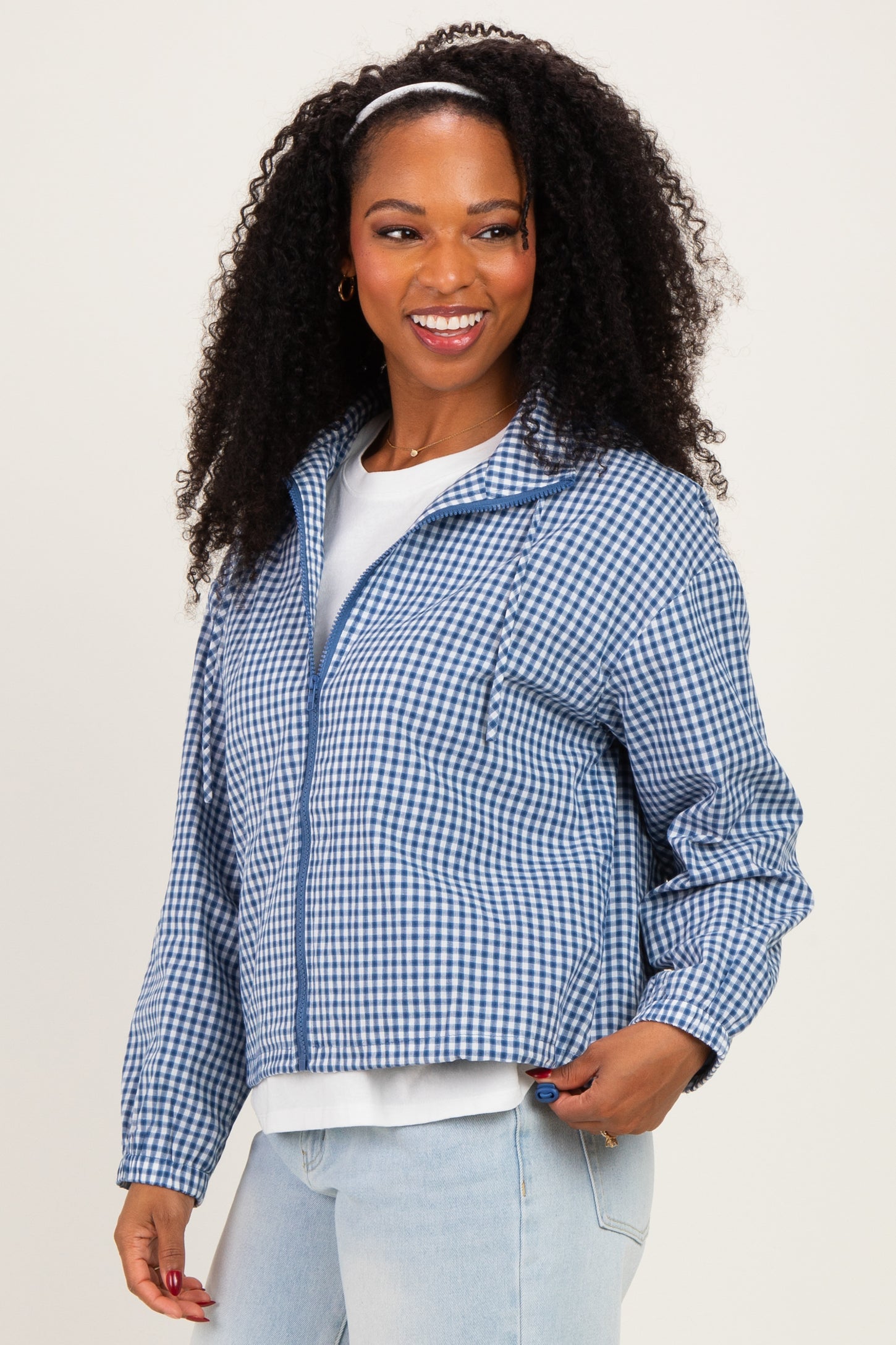 woman wearing a blue and white gingham cropped jacket with a zipper and front pockets