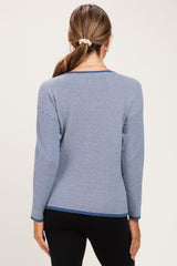 woman wearing a striped blue maternity sweater with long sleeves, view of the back, paired with black leggings