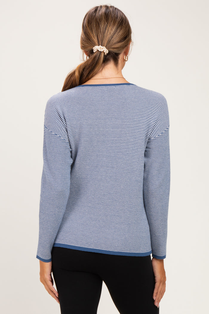 woman wearing a striped blue maternity sweater with long sleeves, view of the back, paired with black leggings