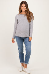 woman wearing a grey long sleeve maternity top and blue rolled cuff jeans, showing a visible baby bump