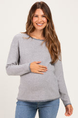 woman wearing a gray and white striped long sleeve maternity top and holding her baby bump
