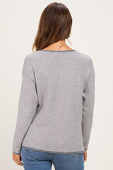woman wearing a gray striped maternity sweater, shown from the back, paired with blue jeans