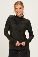 woman wearing a black long sleeve top with floral print and a mock neck, smiling at the camera