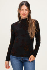 woman wearing a black floral long sleeve maternity top with a high neckline and holding her baby bump