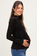 woman wearing a black long sleeve maternity top with floral details, smiling and showing her baby bump
