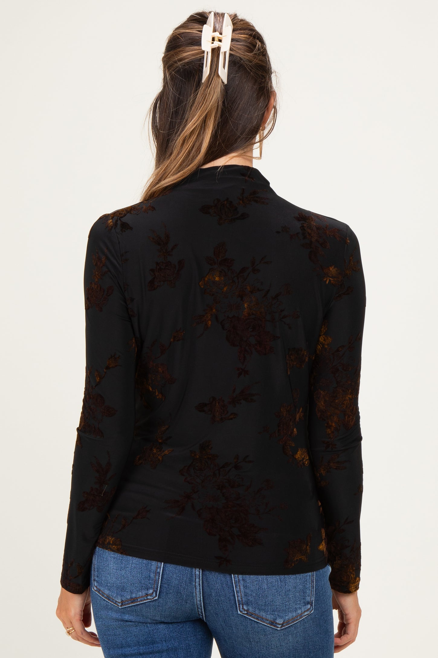 woman wearing a black long sleeve maternity top with floral pattern, view showing the back design