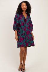 woman wearing a teal floral print dress with short sleeves and a relaxed fit, standing in a pose