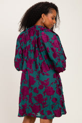 woman wearing a teal dress with a maroon floral print and gathered detailing at the back