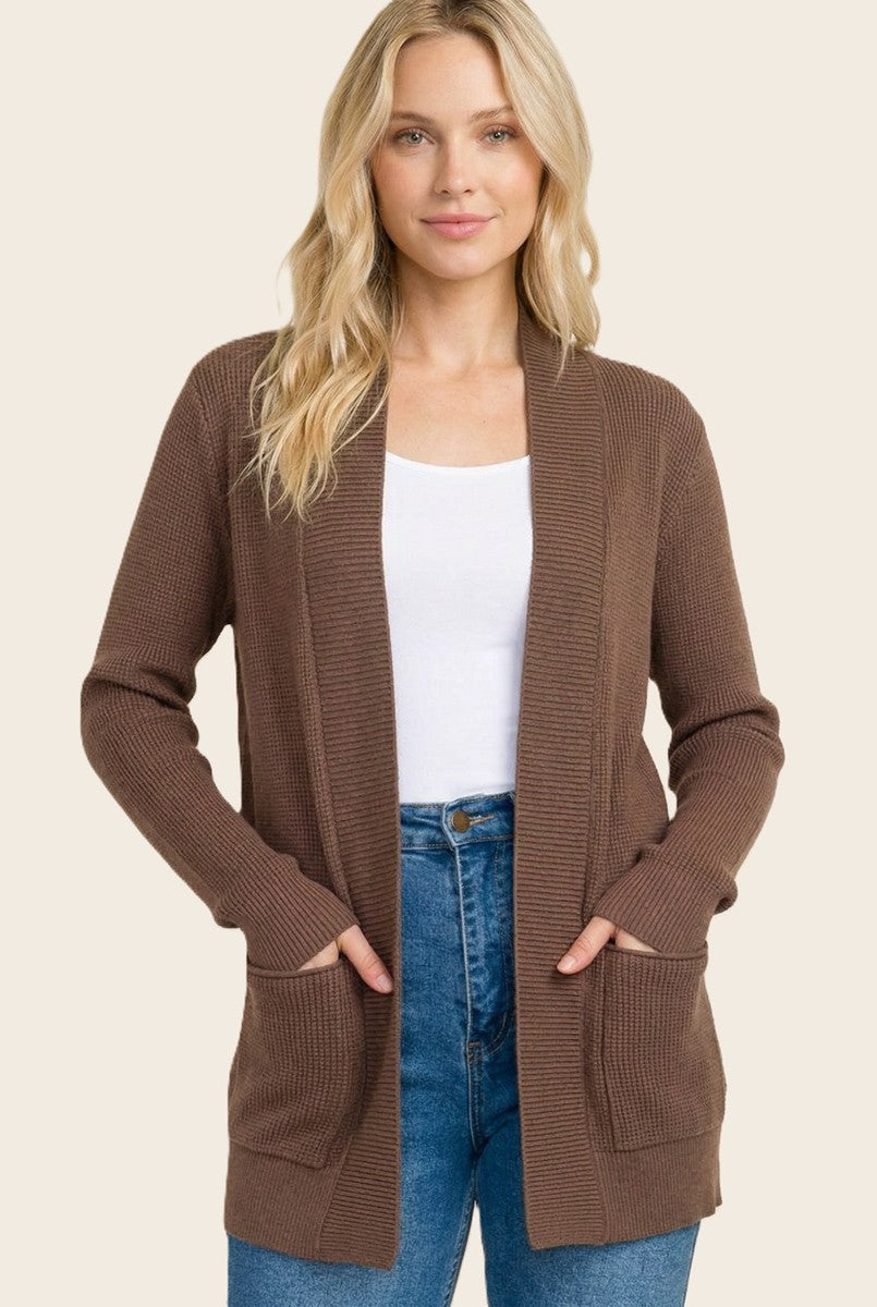 woman wearing a brown ribbed cardigan with pockets and a white tank top, styled with blue high-waisted jeans