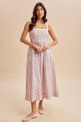 woman wearing a pink floral midi dress with square neckline and shoulder straps, standing on a beige background