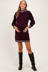 woman wearing a dark purple maternity sweater dress with striped collar and cuffs, showing her baby bump