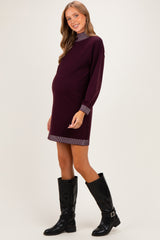 woman wearing a burgundy maternity dress with striped cuffs and a baby bump visible