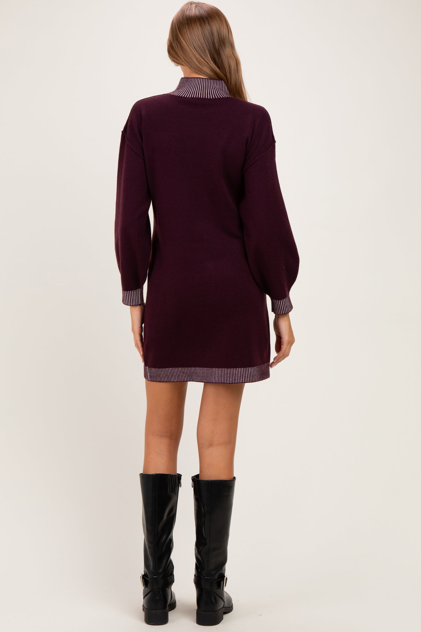 woman wearing a burgundy maternity sweater dress with striped collar and cuffs, seen from the back