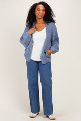 woman wearing a light blue oversized knit cardigan over a white top and blue wide-leg jeans