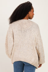 woman wearing a chunky knit beige sweater with a relaxed fit and dropped shoulders, viewed from the back